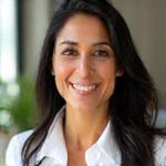 Headshot of Saraห์ Khan, a Registered Dietitian with a friendly smile, in a professional kitchen or consultation room.